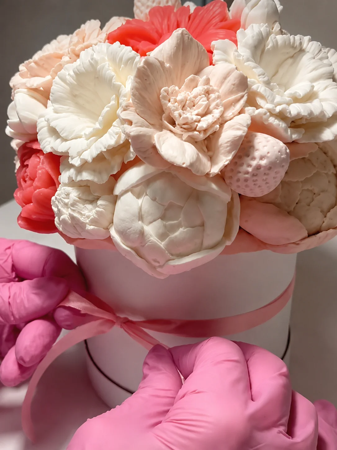A handmade pink and cream marshmallow flower bouquet being finished with ribbon